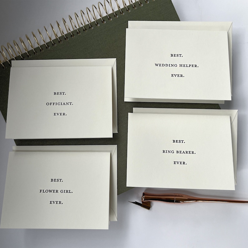May include: Four white cards with black text. The cards read "Best. Officiant. Ever.", "Best. Flower Girl. Ever.", "Best. Wedding Helper. Ever.", and "Best. Ring Bearer. Ever."