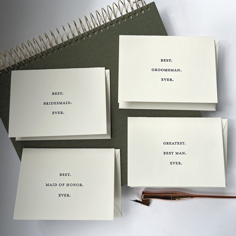 May include: Four white cards with black text on a green background. The cards read "Best. Bridesmaid. Ever.", "Best. Maid of Honor. Ever.", "Best. Groomman. Ever.", and "Greatest. Best Man. Ever."