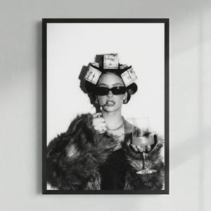 May include: Black and white framed print of a person wearing sunglasses, a fur coat, and money curlers in their hair. They are holding a cigarette and a glass of wine. The image has a glamorous, high-fashion aesthetic.