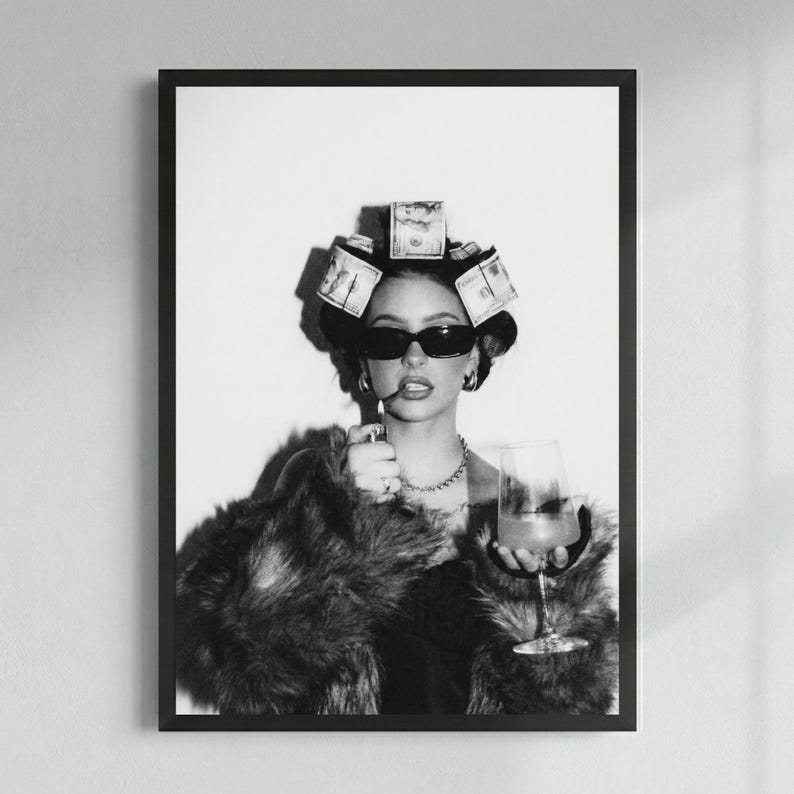 May include: Black and white framed print of a person wearing sunglasses, a fur coat, and money curlers in their hair. They are holding a cigarette and a glass of wine. The image has a glamorous, high-fashion aesthetic.