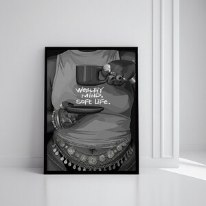 May include: Black and white art print featuring a person wearing a tank top with the text "WEALTHY MIND, SOFT LIFE." The person is holding a mug and saucer, adorned with jewelry and a decorative belt.