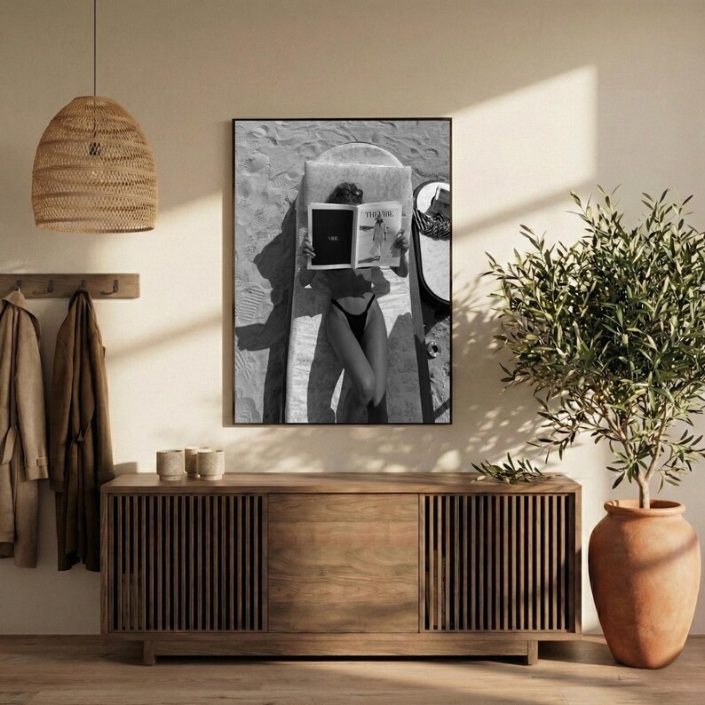 Peut inclure: Impression en noir et blanc encadr&eacute;e d'une personne lisant un magazine sur une planche de surf. L'image est prise d'en haut, montrant la personne en maillot de bain noir. La couverture du magazine est visible, avec le mot "THE" affich&eacute;.