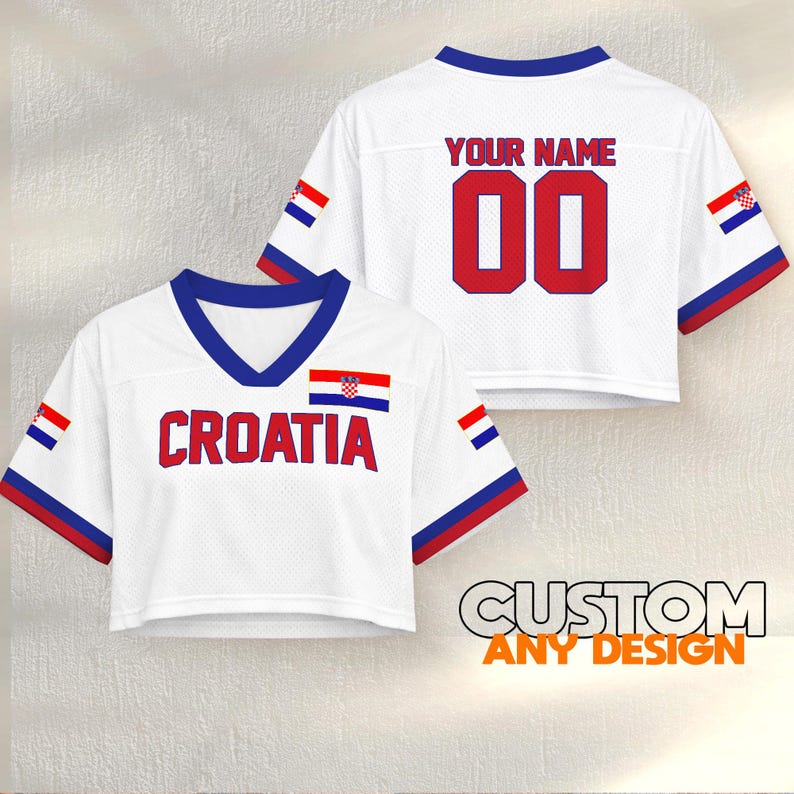 K&ouml;nnte beinhalten: Wei&szlig;es Crop-Top-Trikot mit "CROATIA" in roten Buchstaben und der kroatischen Flagge. Auf der R&uuml;ckseite steht "YOUR NAME" &uuml;ber der Nummer "00" in Rot. Blaue und rote Akzente an &Auml;rmeln und Ausschnitt. "CUSTOM ANY DESIGN" ist unten aufgedruckt.