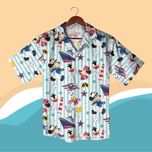 May include: Short-sleeved button-down shirt with a nautical theme. The shirt features a light blue and white striped background with cartoon characters, ships, anchors, and stars. The characters include Mickey and Minnie Mouse, and Donald Duck.