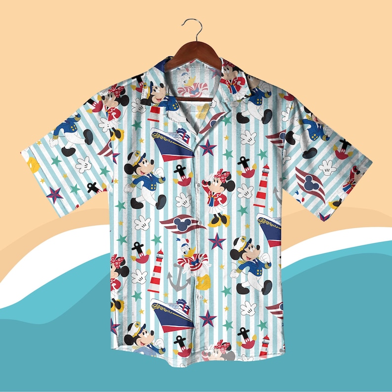 May include: Short-sleeved button-down shirt with a nautical theme. The shirt features a light blue and white striped background with cartoon characters, ships, anchors, and stars. The characters include Mickey and Minnie Mouse, and Donald Duck.