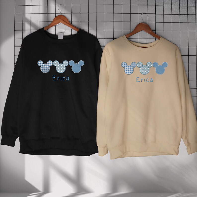 May include: Two black and beige sweatshirts with a blue and white Mickey Mouse design and the name "Erica" printed on each.