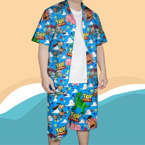 K&ouml;nnte beinhalten: Ein blaues kurz&auml;rmeliges Hemd und ein passendes Shorts-Set mit Figuren aus dem Film Toy Story. Das Set enth&auml;lt Woody, Buzz Lightyear und andere Charaktere, mit den Worten "Toy Story" &uuml;berall gedruckt.
