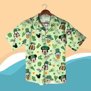 Może przedstawiać: Jasnozielona koszula zapinana na guziki z różnymi postaciami Disneya w zielonych kapeluszach i koniczynach. Myszka Miki, Kaczor Donald, Goofy i Pluto to jedne z postaci. Koszula ma krótkie rękawy i klasyczny kołnierzyk.