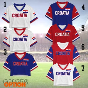 K&ouml;nnte beinhalten: Sieben kurz geschnittene V-Ausschnitt-Shirts in Wei&szlig;, Blau und Rot, jeweils mit dem Schriftzug "CROATIA" und der kroatischen Flagge. Die Shirts haben kontrastierende &Auml;rmel- und Ausschnittdetails. Verschiedene Farboptionen werden gezeigt.