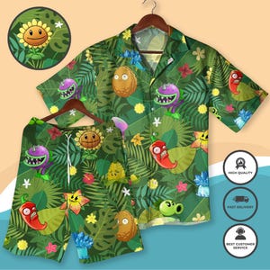 Puede incluir: Conjunto de camisa y pantalón corto verdes con un estampado de plantas tropicales. El diseño presenta girasoles de dibujos animados, chiles y otras plantas sobre un fondo verde oscuro. La camisa tiene mangas cortas y cuello, y el pantalón corto tiene cordón.