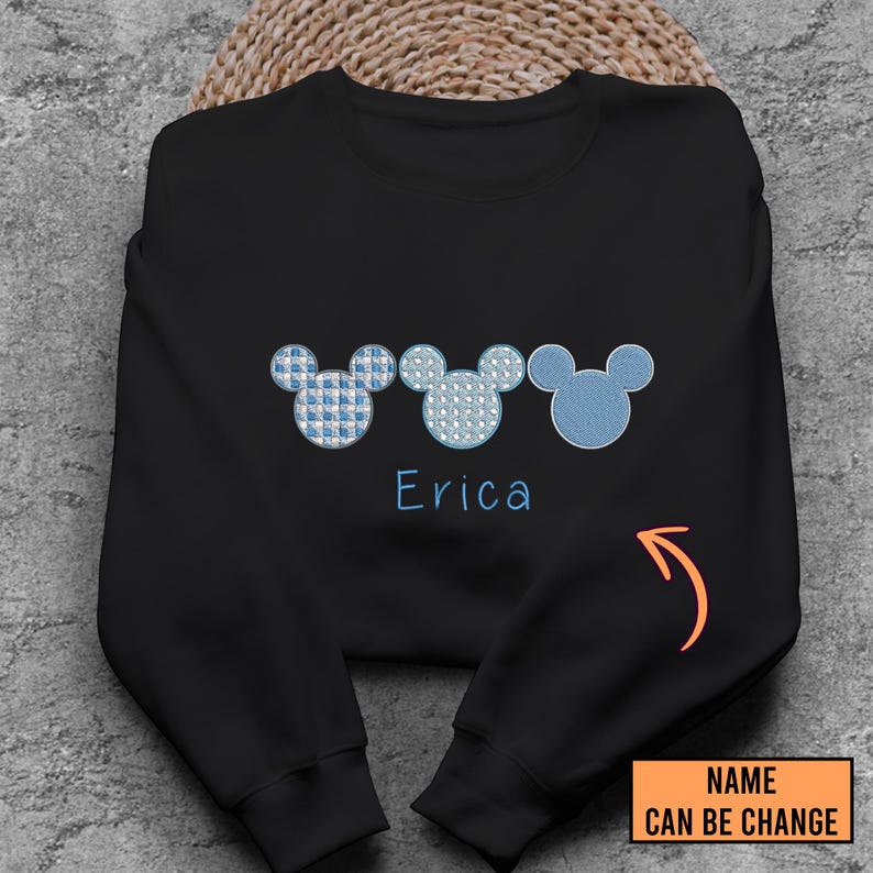 May include: Black sweatshirt with three blue and white Mickey Mouse heads and the name "Erica" printed below. The text "NAME CAN BE CHANGE" is visible in the bottom right corner.