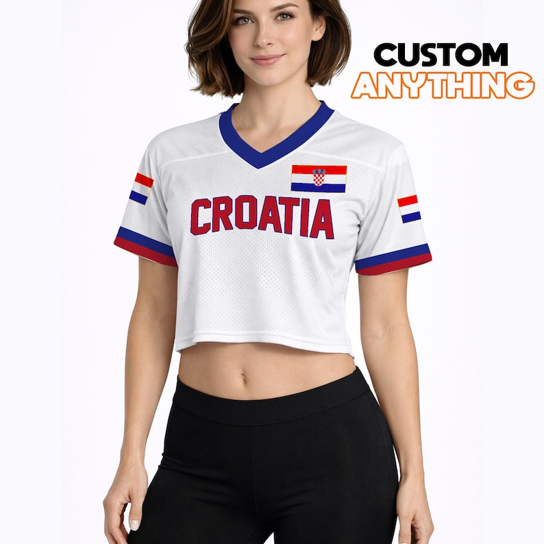 K&ouml;nnte beinhalten: Wei&szlig;es Crop-Top mit blauem V-Ausschnitt und roten und blauen Akzenten. Das Shirt tr&auml;gt das Wort "CROATIA" in roten Blockbuchstaben und die kroatische Flagge. Der Text "CUSTOM ANYTHING" ist orange.