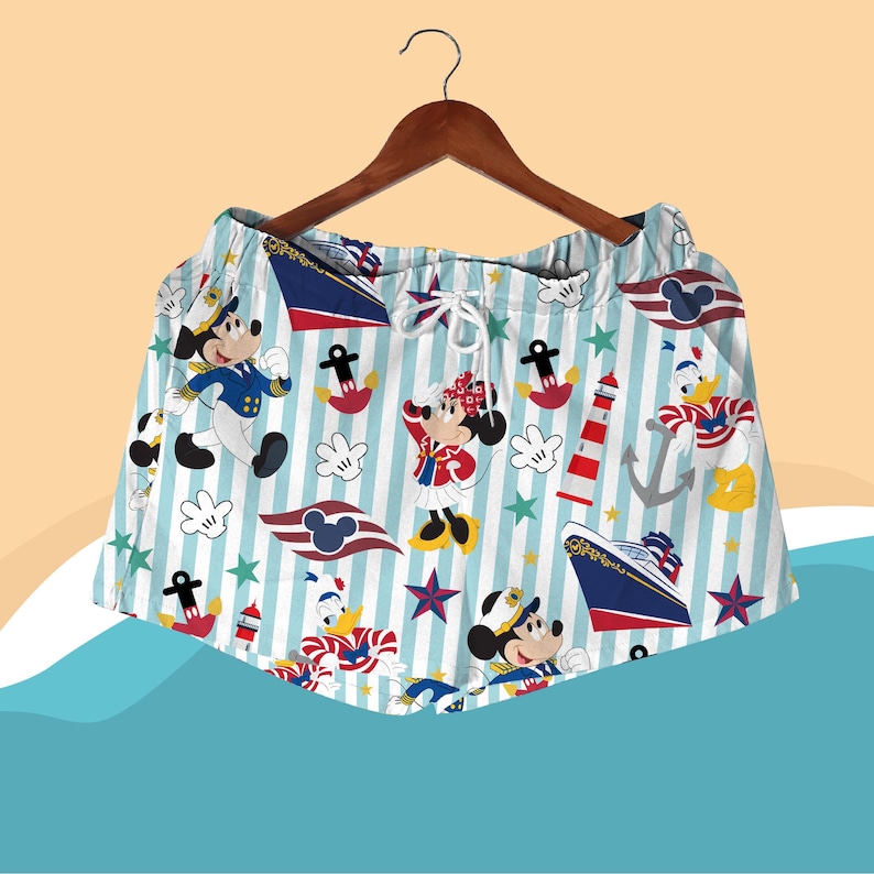 May include: Light blue and white striped shorts featuring cartoon characters Mickey Mouse, Minnie Mouse, and Donald Duck in nautical attire. The shorts have a drawstring waist and are decorated with anchors, stars, and a cruise ship.