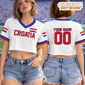 K&ouml;nnte beinhalten: Wei&szlig;es Crop-Top-Trikot mit blauen und roten Akzenten. Auf der Vorderseite steht "CROATIA" in roten Buchstaben und eine kroatische Flagge. Auf der R&uuml;ckseite steht "YOUR NAME" &uuml;ber der Nummer "00" in Rot. "CUSTOM ANY DESIGN" ist oben aufgedruckt.