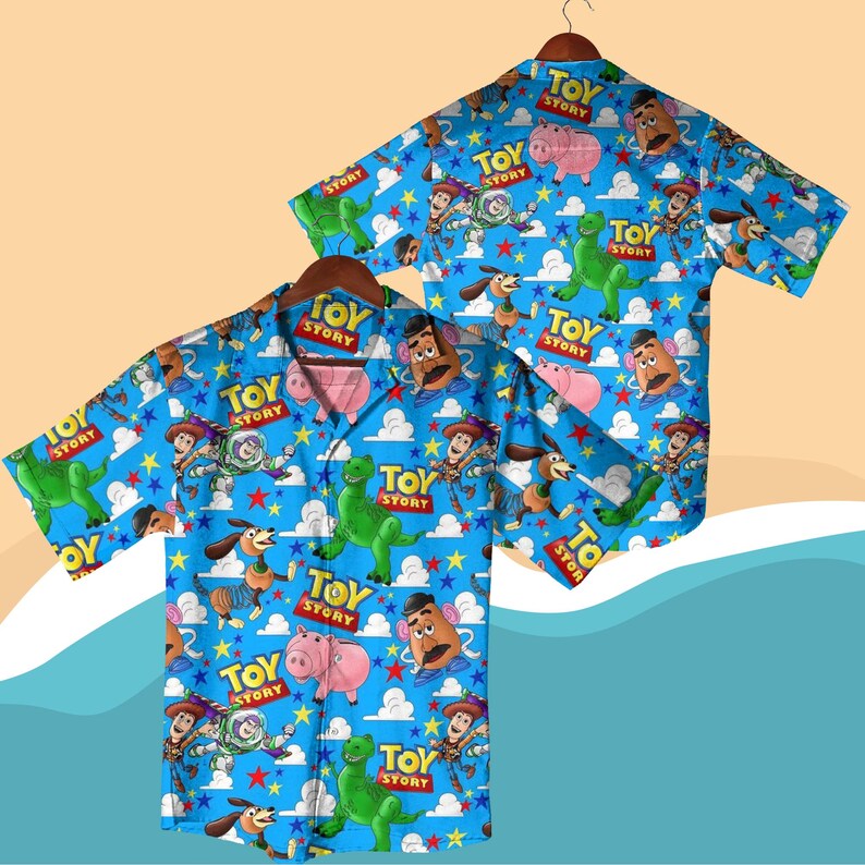 K&ouml;nnte beinhalten: Zwei kurz&auml;rmelige Button-Down-Hemden mit blauem Hintergrund und einem sich wiederholenden Muster von Charakteren aus dem Film "Toy Story". Die Hemden zeigen Woody, Buzz Lightyear, Rex, Mr. Potato Head, Hamm und Slinky Dog.