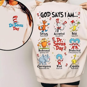 Puede incluir: Sudadera color crema con personajes del Dr. Seuss y el texto "GOD SAYS I AM...". El diseño incluye varios personajes con palabras inspiradoras como "Fuerte", "Aceptado" y "Audaz". Una imagen más pequeña en el frente muestra el logo del Día del Dr. Seuss.