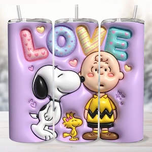 Puede incluir: Un juego de tres vasos de acero inoxidable con un fondo lavanda que presenta a Snoopy, Charlie Brown y Woodstock. La palabra "LOVE" se muestra en letras coloridas y texturizadas. Cada vaso tiene una pajita y una tapa.