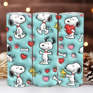 May include: Three stainless steel tumblers with a repeating pattern of Snoopy, hearts, paw prints, and bones on a light blue background. The cartoon dog is in various poses, with a red collar.
