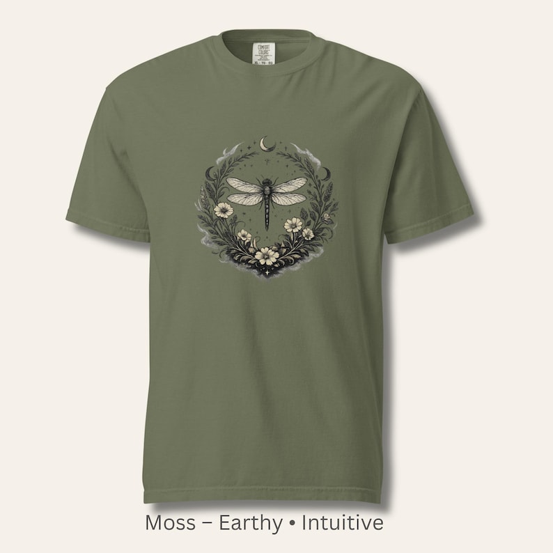 Flat lay of a Comfort Colors 1717 t-shirt in Moss green with a detailed dragonfly and botanical sigil. Earthy, nature-coded, witchy aesthetic. Garment-dyed cotton with vintage softness. Ideal for intuitive women and botanical art lovers.