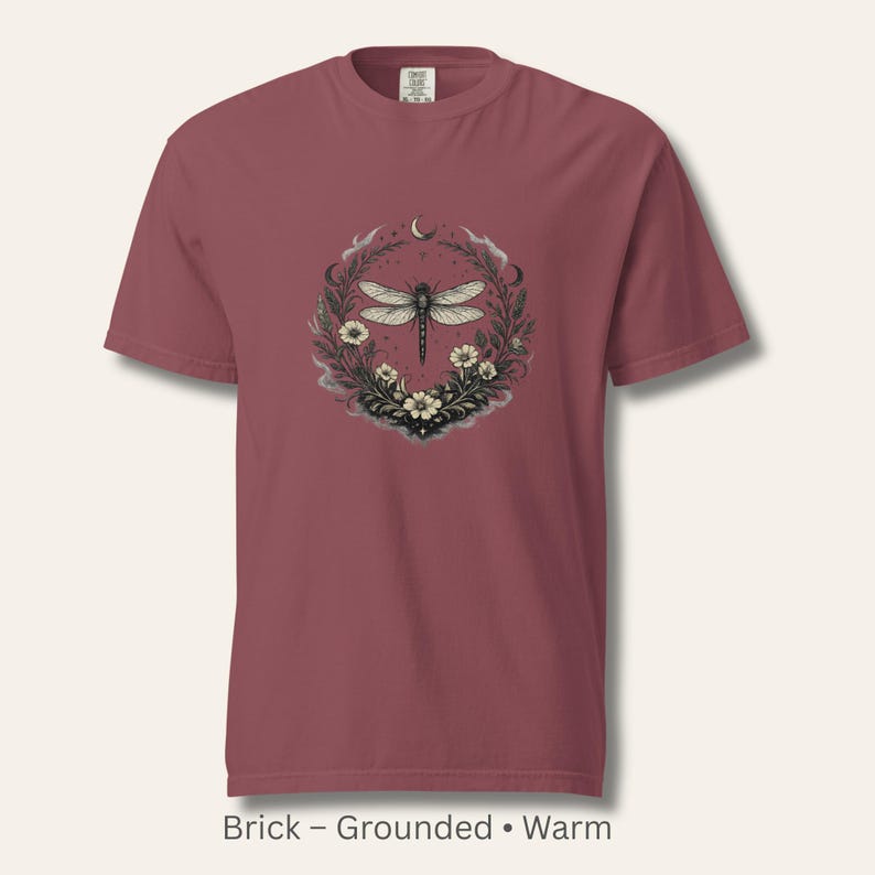 Flat lay of a Comfort Colors 1717 t-shirt in Brick, showcasing the Dragonfly Sigil with wildflowers and crescent moon. Warm, grounded, vintage-washed cotton. Perfect for dark feminine, witchy, and nature-inspired wardrobes.