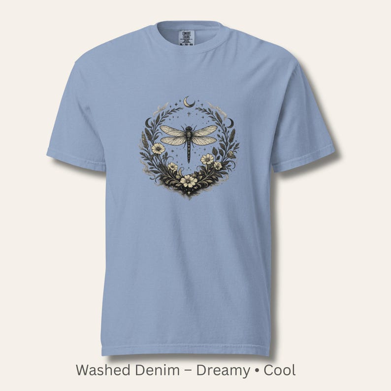 Flat lay of a Comfort Colors 1717 t-shirt in Washed Denim blue featuring the Dragonfly Sigil with botanical elements. Soft, dreamy, vintage-washed cotton. Ideal for intuitive women, witchy aesthetics, and symbolic clothing.