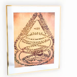 May include: Framed artwork featuring an abstract design with the word "Allah" at the top. The artwork has a warm color palette with shades of orange and brown. The frame is gold-colored, adding a touch of elegance to the piece.