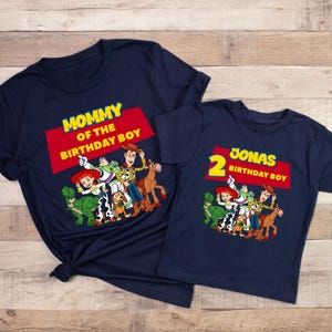 May include: Two navy blue t-shirts with a Toy Story theme. The larger shirt says "Mommy of the Birthday Boy" and features the characters Woody, Buzz Lightyear, Jessie, Rex, Slinky Dog, and Bullseye. The smaller shirt says "2 Jonas Birthday Boy" and features the same characters.
