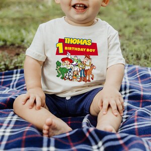 May include: A white t-shirt with a red, yellow, and blue Toy Story character graphic. The shirt has the text "Thomas 1 Birthday Boy" on the front.
