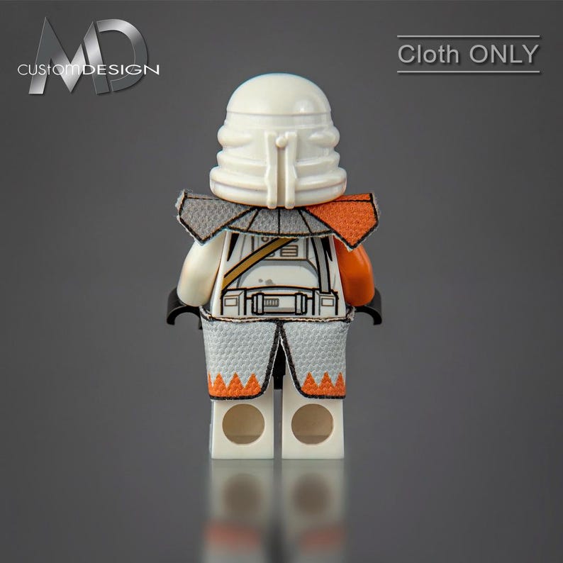May include: A white and orange Lego minifigure with a white helmet and a gray and orange cloth armor. The minifigure is standing on a gray surface. "Cloth ONLY" is written in white text on a black background in the upper right corner of the image.