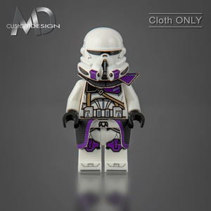 May include: A white LEGO minifigure with a purple and black cloth cape and a white helmet with purple and black details. The minifigure is wearing a white and black armour with gold accents. The text "Cloth ONLY" is visible in the upper right corner of the image.