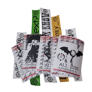 May include: A collection of stickers with various designs, including a black and white illustration of a person with a mohawk, a black and white illustration of a bird, a black and white illustration of a bat, and text that reads "ALL LOVE LIGHTSOUNDDIMENSION.COM".