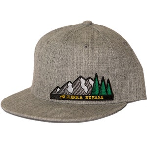 Puede incluir: Gorra de béisbol gris y negra con un parche bordado que representa una cordillera y árboles con el texto "The Sierra Nevada".
