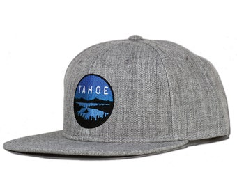 May include: Gray and blue embroidered baseball cap with the word "TAHOE" and a lake scene.