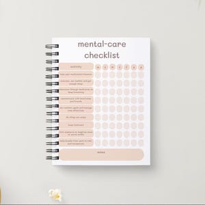 May include: A white mental-care checklist notebook with a spiral binding. The notebook has a pink and white color scheme and includes a list of activities to help with mental health. The activities include taking medication, exercising, getting enough sleep, meditating, and connecting with friends.