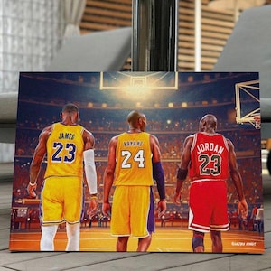 May include: A canvas print featuring three basketball players in their jerseys. LeBron James in a yellow jersey with the number 23, Kobe Bryant in a yellow jersey with the number 24, and Michael Jordan in a red jersey with the number 23.