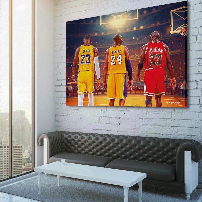 May include: A canvas print featuring three basketball players in their jerseys, viewed from behind. LeBron James in yellow, Kobe Bryant in yellow, and Michael Jordan in red. The background shows a basketball court and stadium.