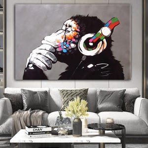 May include: A colorful painting of a monkey wearing headphones. The monkey is sitting and thinking. The background is gray.