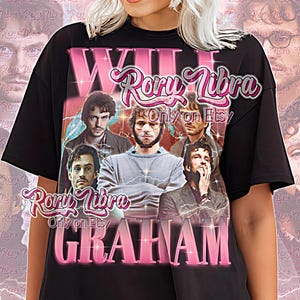 May include: Black unisex t-shirt featuring a pink graphic design with the text "WILL GRAHAM" and "Rory Libra Only on Etsy." The design includes images of several men. The words "Unisex Shirt" are also printed on the shirt.