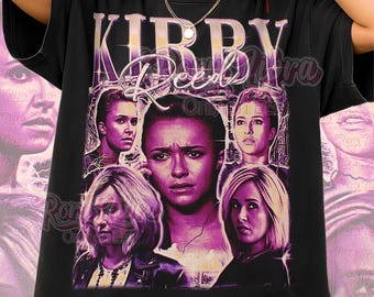 Op de afbeelding: Zwart unisex T-shirt met een grafisch ontwerp met de tekst "Kirby Reed" in paars en wit. Het ontwerp bevat afbeeldingen van verschillende vrouwen in een vintage stijl. De woorden "Unisex Shirt" staan onderaan.