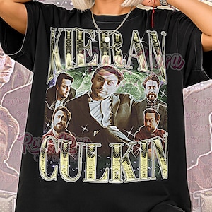 May include: Black unisex t-shirt featuring a graphic of Kieran Culkin with the text "Kieran Culkin" in gold lettering. The shirt also has the words "Unisex Shirt" in pink script at the bottom.