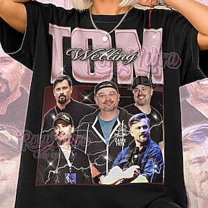 Op de afbeelding: Zwart unisex T-shirt met een groepsfoto en de tekst "TON Wedding Libra". Het ontwerp is vintage, met roze en witte letters. De tekst "ZAIRE 197" is ook zichtbaar.