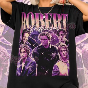 Op de afbeelding: Zwart unisex T-shirt met een afbeelding van Robert Pattinson en de tekst "ROBERT Pattinson" in een paarse en roze gradiënt. Het ontwerp heeft een vintage uitstraling, met een collage van afbeeldingen van de acteur. De woorden "Unisex Shirt" staan onderaan.