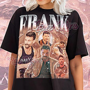 May include: Black unisex t-shirt featuring a graphic of Frank Grillo with the word "FRANK" in silver block letters. The shirt includes multiple images of the actor and the text "Grillo" in a script font. The shirt is a vintage style.