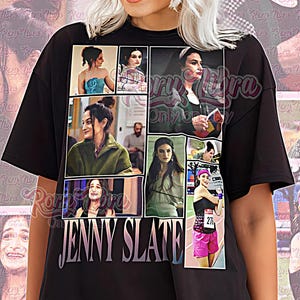 Pode incluir: Camiseta unissex preta com uma colagem de imagens e o nome "JENNY SLATE" em branco. A camiseta também tem o texto "Unisex Shirt" em rosa. A pessoa na imagem está usando a camiseta.