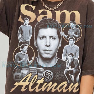 May include: A dark brown t-shirt featuring a large black and white portrait of Sam Altman in the centre, surrounded by smaller photos of him in various poses. The text Sam appears at the top and Altman at the bottom in a tan script font.