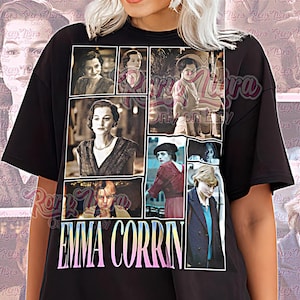 May include: Black unisex t-shirt featuring a collage of images of Emma Corrin. The shirt has the name "EMMA CORRIN" in a gradient font. The words "Unisex Shirt" are printed at the bottom of the shirt.