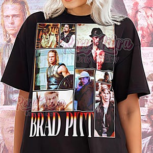 Può includere: T-shirt unisex nera con un collage di immagini di Brad Pitt. La maglietta mostra il nome "BRAD PITT" in lettere bianche. Le parole "Unisex Shirt" sono stampate nella parte inferiore della maglietta.