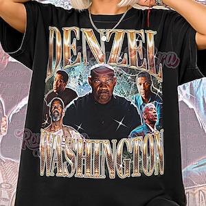 May include: Black unisex t-shirt featuring a graphic of Denzel Washington with the text "Denzel Washington" in a vintage style. The shirt also has the text "Unisex Shirt" at the bottom. The shirt is worn by a person.