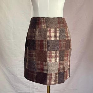 Puede incluir: Una minifalda de cuadros marrones, grises y rojos con un diseño de patchwork.