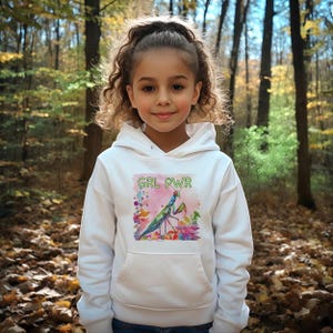 Könnte beinhalten: Weißer Hoodie mit einem grünen, blauen und rosa Grafikdruck einer Gottesanbeterin mit dem Text "GRL PWR" in grün.